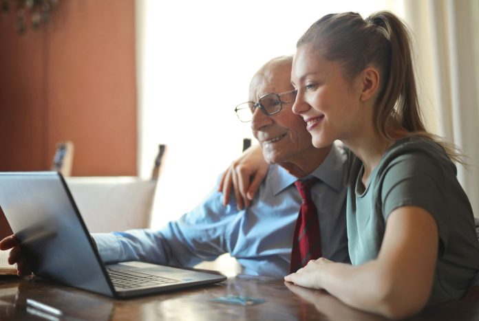 young positive woman helping senior man using laptop 3823489
