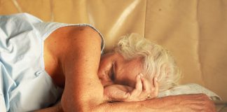 old grey haired woman sleeping on bed scaled