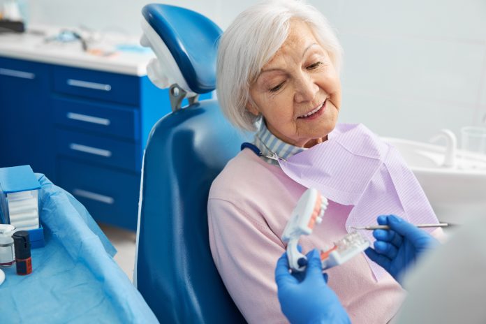 Senior citizen listening to orthodontist explanation of human teeth