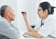 Female Doctor checking to senior man patient eyes.