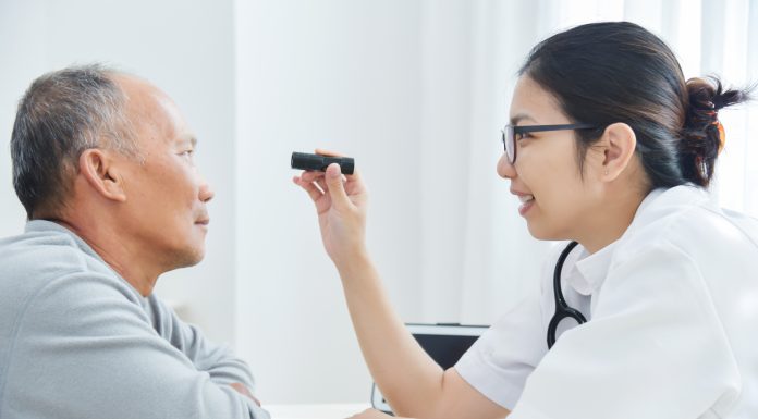 Female Doctor checking to senior man patient eyes.