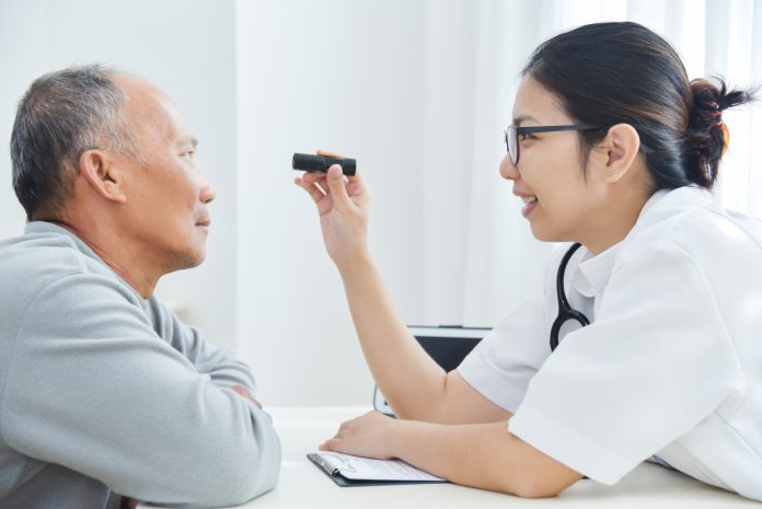 Female Doctor checking to senior man patient eyes.