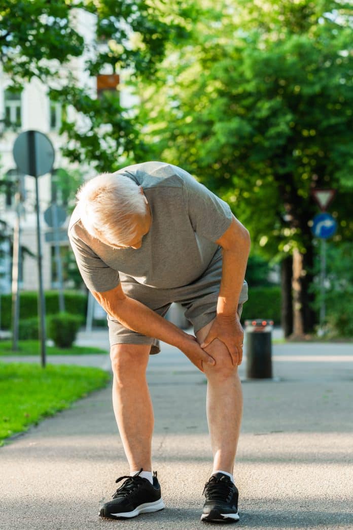 Elderly man suffering from knee pain during his jogging workout