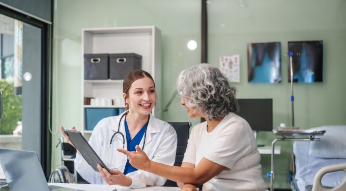 Monthly health check ups and counseling sessions are provided to an elderly Asian woman by a Caucasian female caregiver, offering support, advice, and motivation.