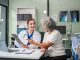 Monthly health check ups and counseling sessions are provided to an elderly Asian woman by a Caucasian female caregiver, offering support, advice, and motivation.